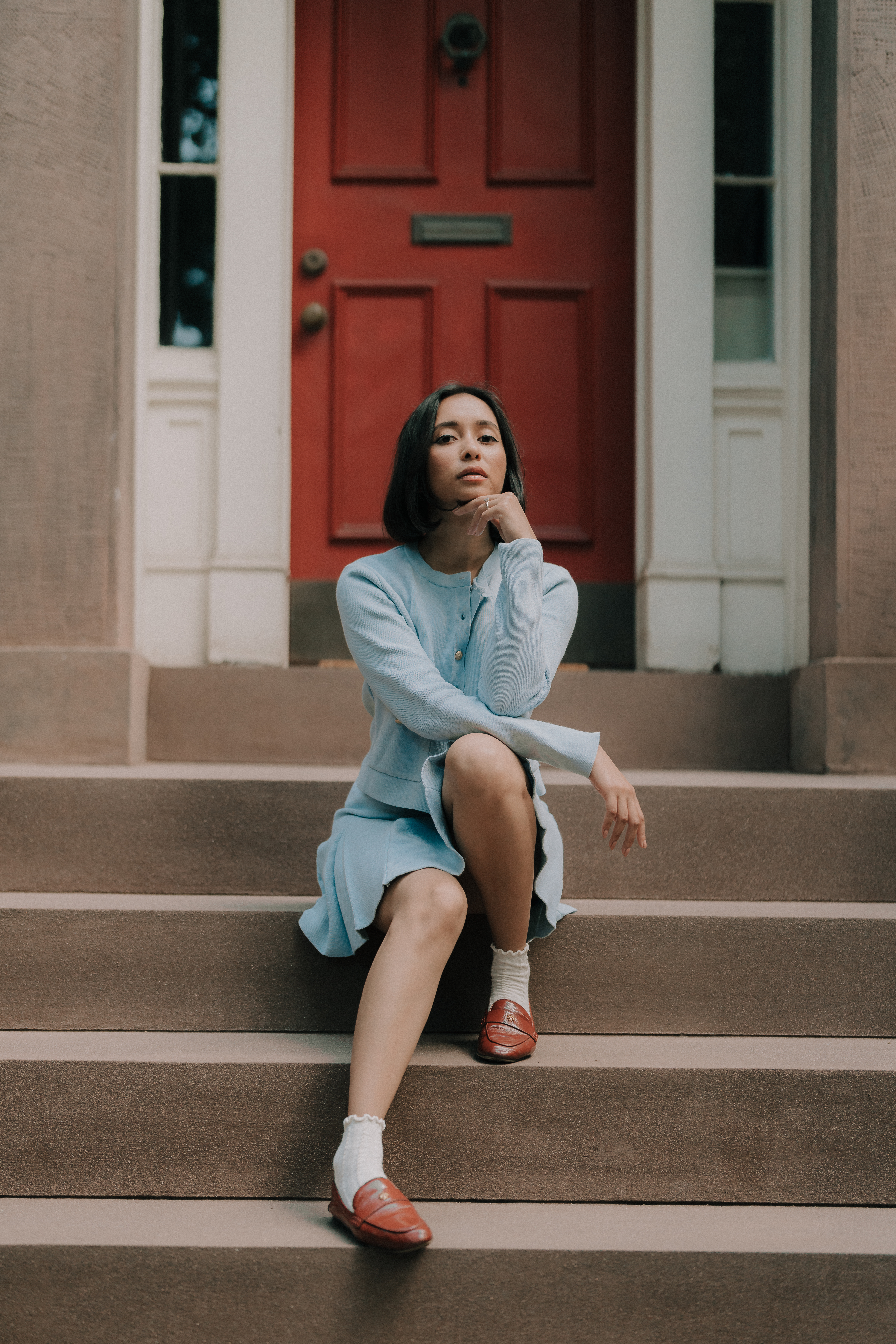 Raisa Ahmed on brownstone steps by a red door
