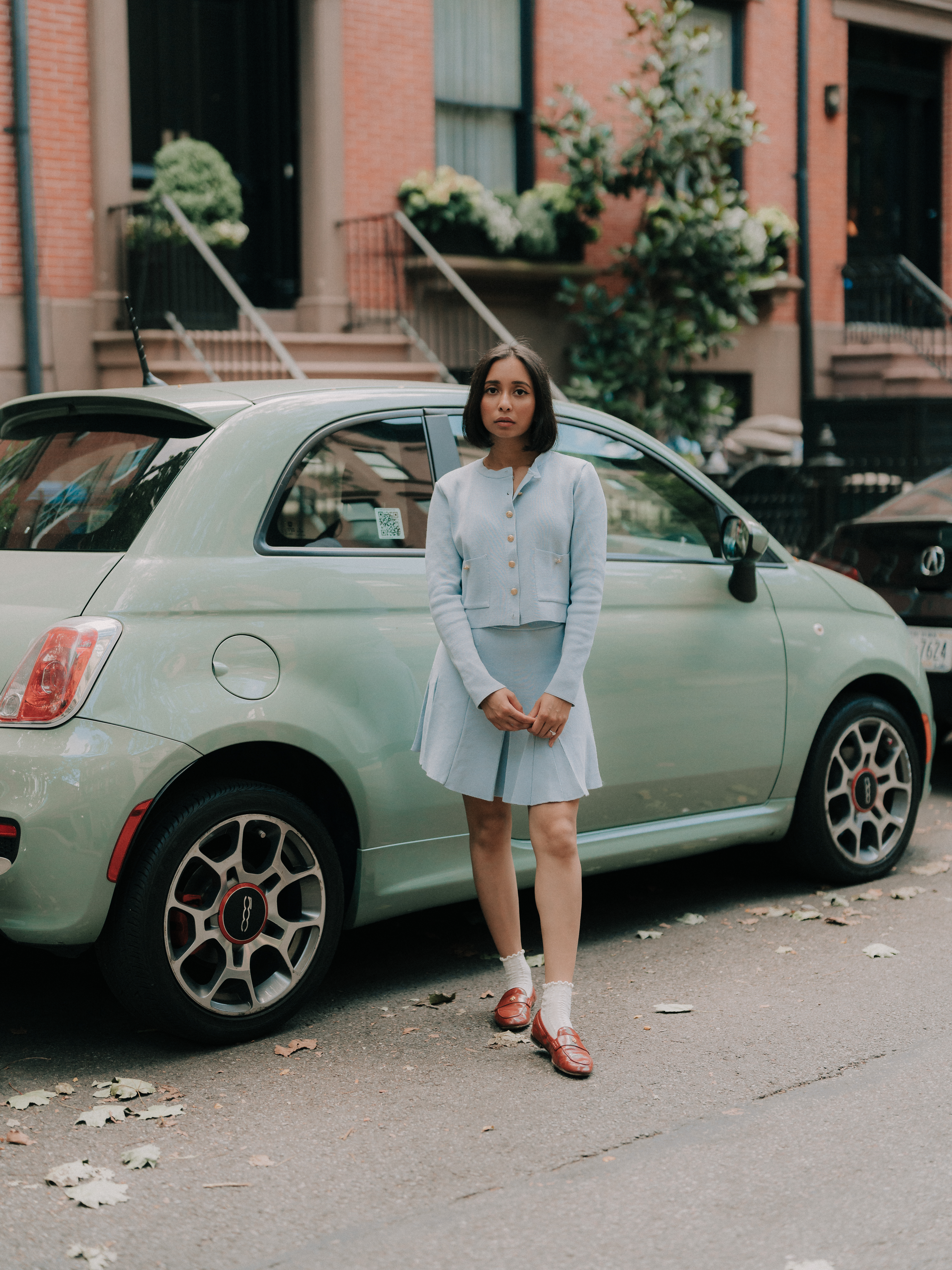 Raisa Ahmed in light-blue knit beside a mint-green Fiat